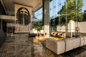 A spacious lobby with a large sofa, a coffee table, and a decorative wall feature. - TERRA COTA | Stylish 3BR | Americana (Guadalajara)