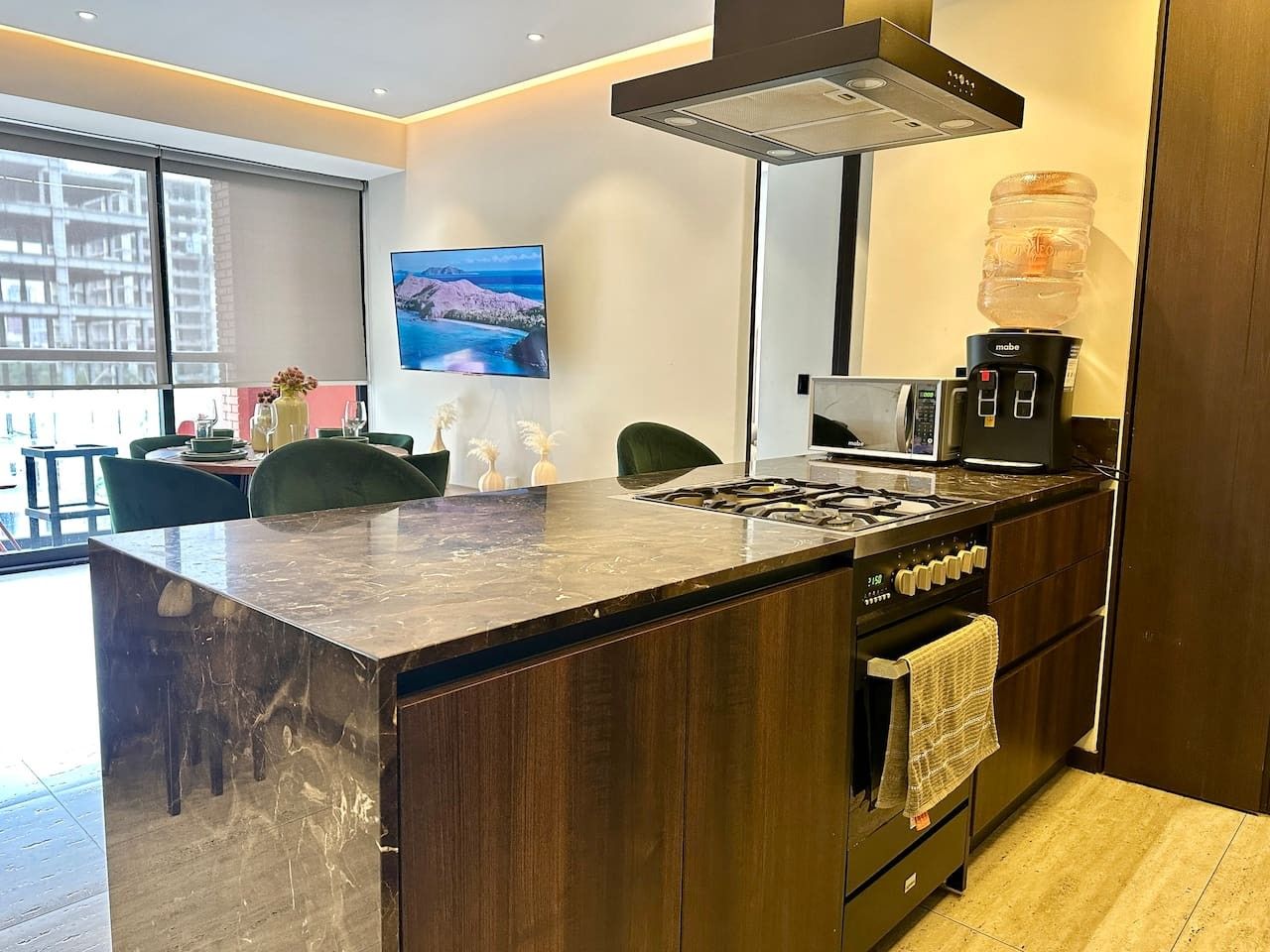 Een moderne keuken met een groot eiland, een inbouwoven en een koffieapparaat.