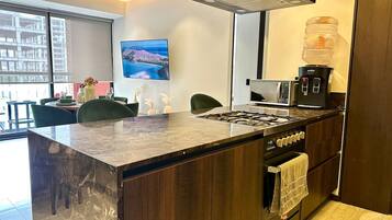 Een moderne keuken met een groot eiland, een inbouwoven en een koffieapparaat.