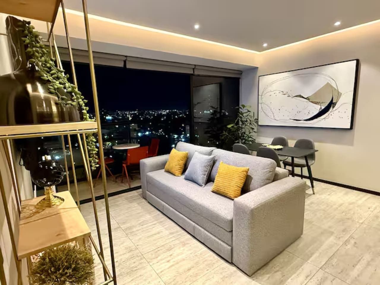 A modern living room with a sofa, a dining table, and a city view.
