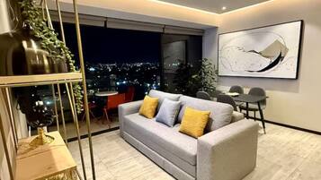 A modern living room with a sofa, a dining table, and a city view.