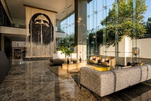 A spacious lobby with a large sofa, a coffee table, and a decorative wall feature. - AUREA | Luxury 2BR Rooftop Pool | Americana (Guadalajara)