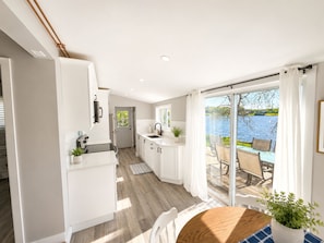 A modern kitchen with a view of a lake through large sliding glass doors. - 2-bedroom Waterfront Rustic Cabin w. Hot Tub/Fire Pit (Trent Hills)