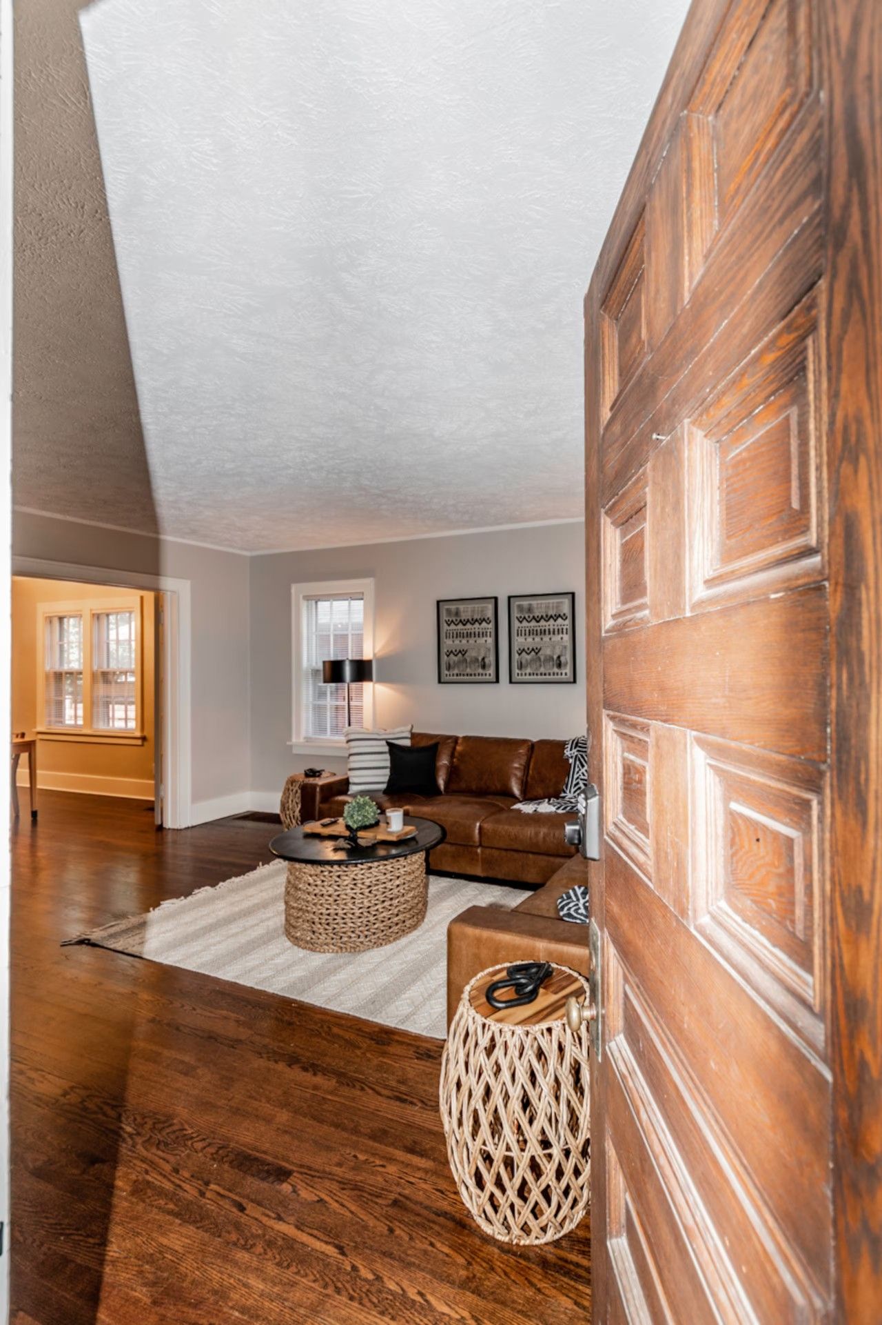 A living room with a brown leather sofa, a round coffee table, and a woven side table.