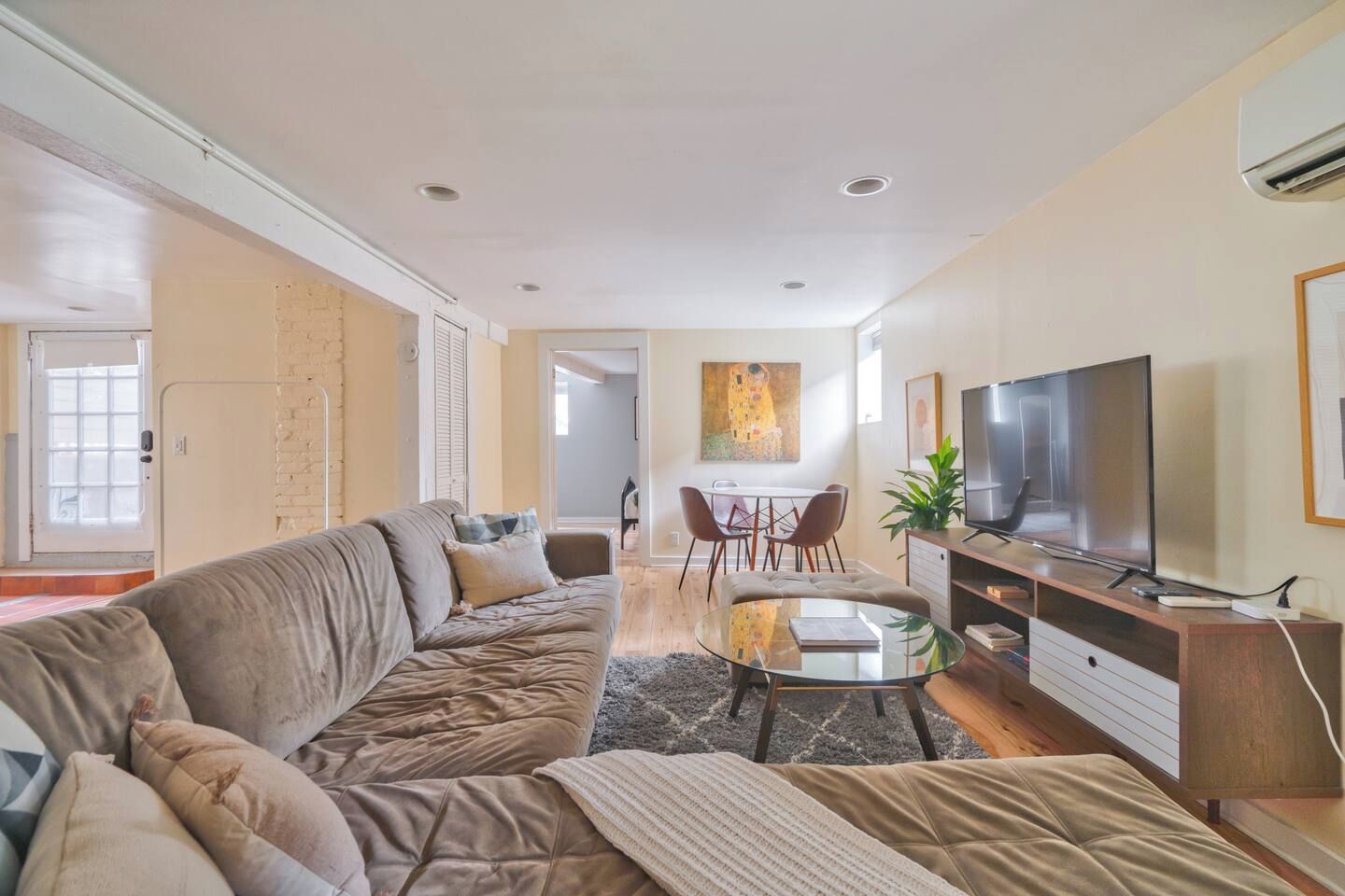 A living room with a sofa, a glass coffee table, a TV, and a dining area with chairs.