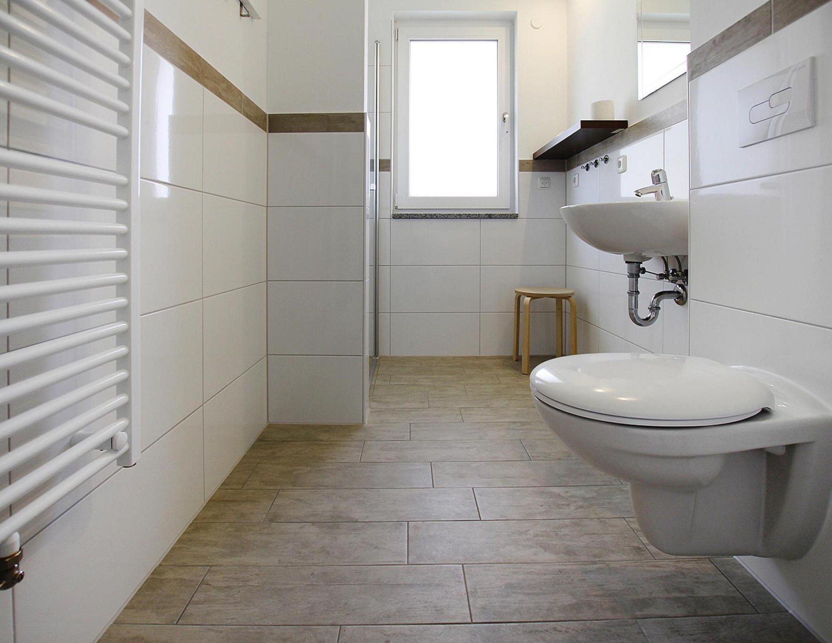 Ein Badezimmer mit Toilette, Waschbecken und einem kleinen Hocker.