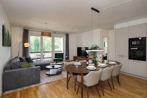 A modern living room with a dining area, large windows, and a kitchen with appliances. - Luxury 4-room Apt in Boutique-style I Prime Location I Family-friendly I Balcony I Kitchen I Netflix I Free Parking I 110 m2 (Eltville am Rhein)