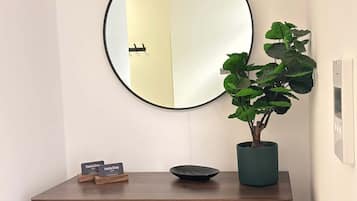 Een houten console met een spiegel, een potplant en een paar naamplaatjes.