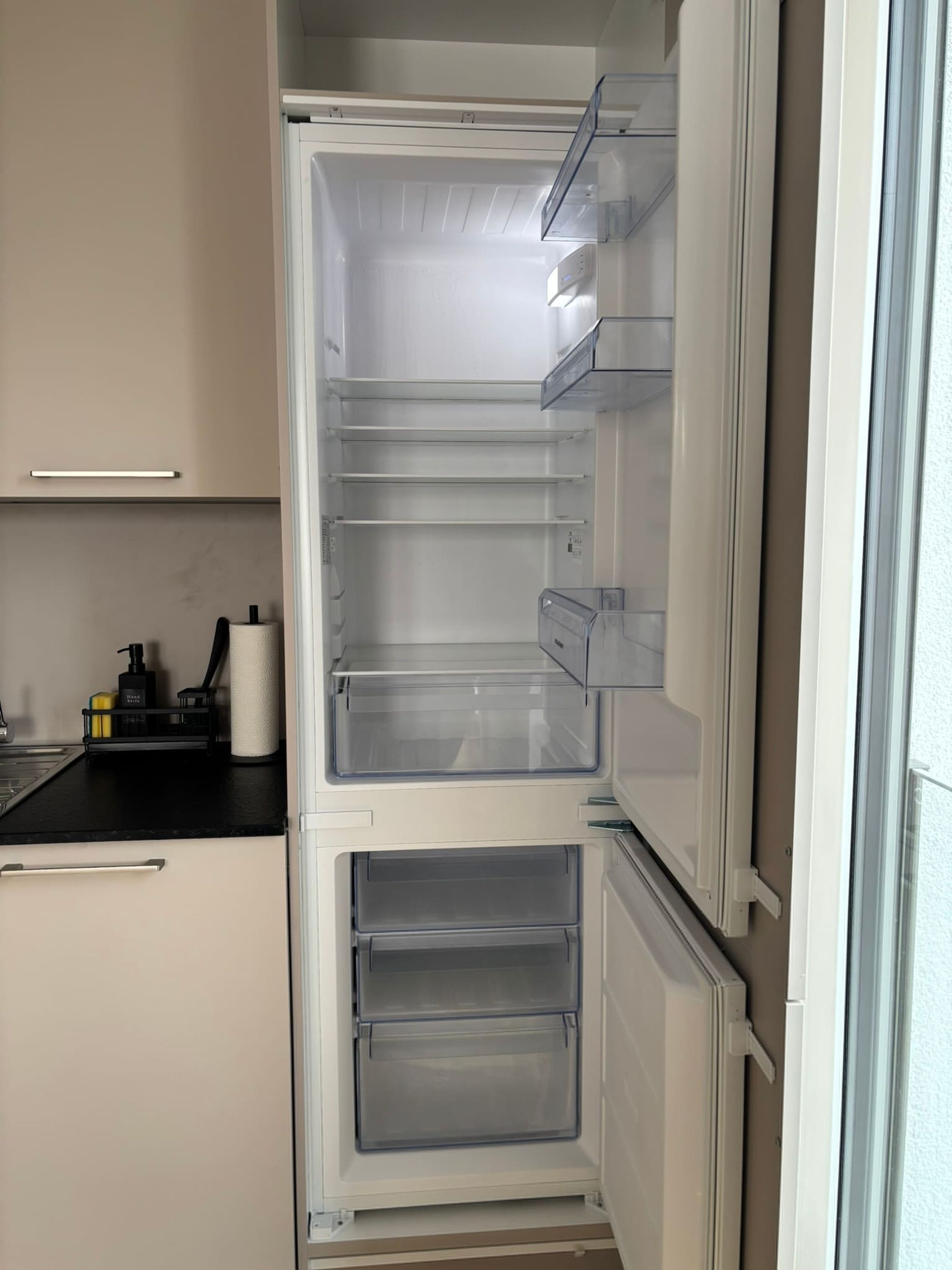 Keittiössä on sisäänrakennettu jääkaappi, työtaso ja seinälle asennettu uuni.
