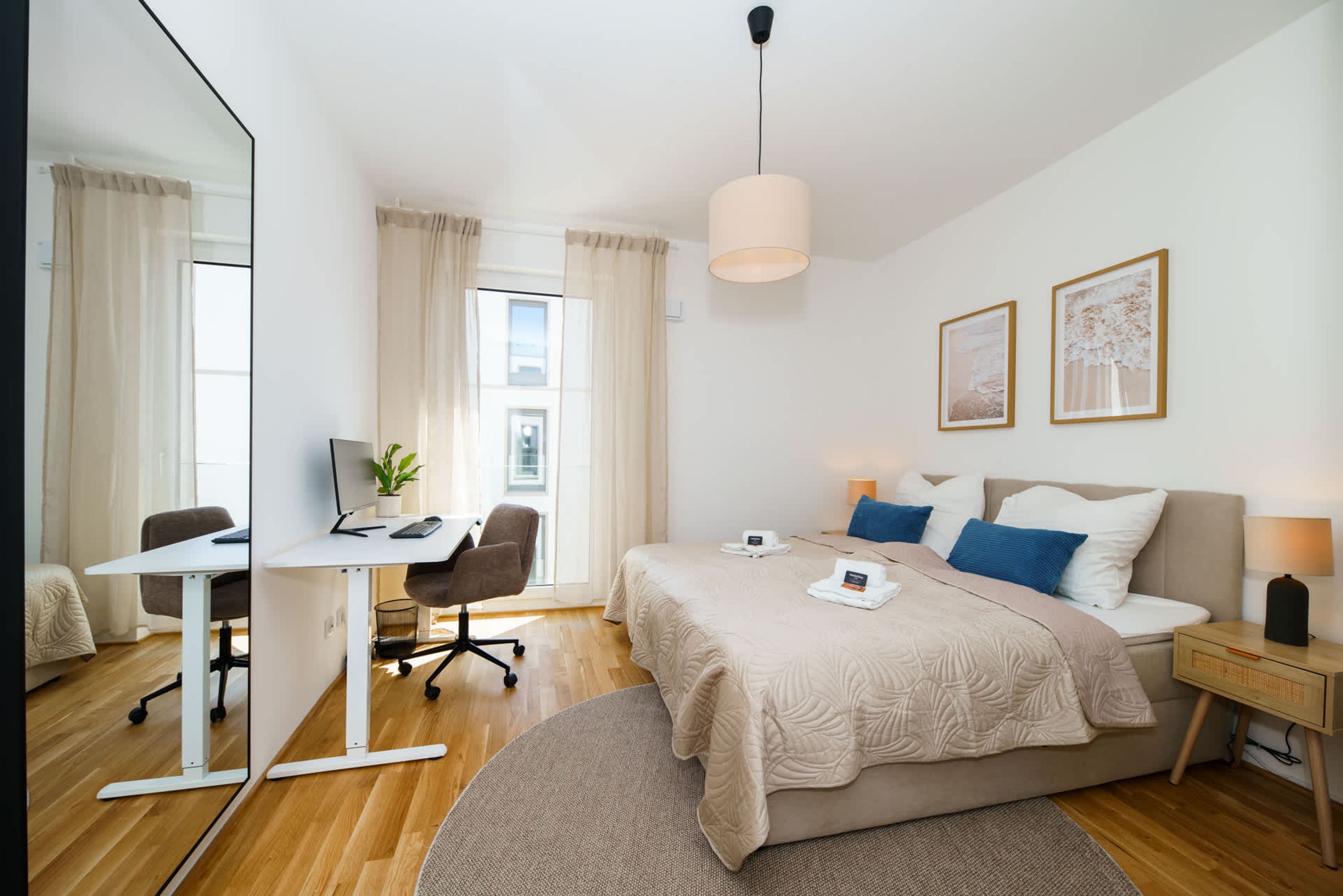 A modern hotel room with a bed, desk, chair, and a large window.