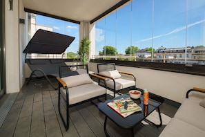 Un balcon avec deux chaises, une table et un magazine.