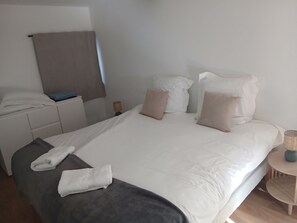Une chambre d’hôtel avec un lit, une table de chevet, une lampe et une petite table ronde sur laquelle est posée une bougie.