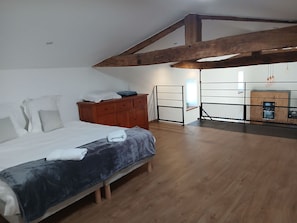 Un dormitorio con cama, cómoda de madera y vista a una zona de cocina.