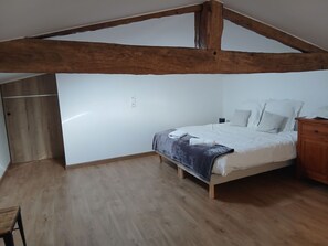 A bedroom with a wooden ceiling, a bed with white bedding, a nightstand, and a wooden floor. - Countryside cottage near Puy du Fou - 6 guests (Les Herbiers)