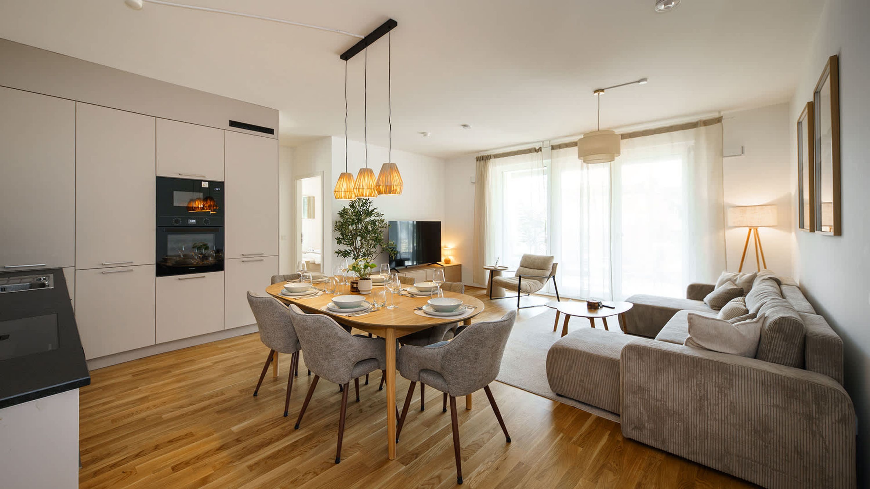 Une cuisine moderne avec un coin repas, un salon avec un canapé et un fauteuil, et un téléviseur.