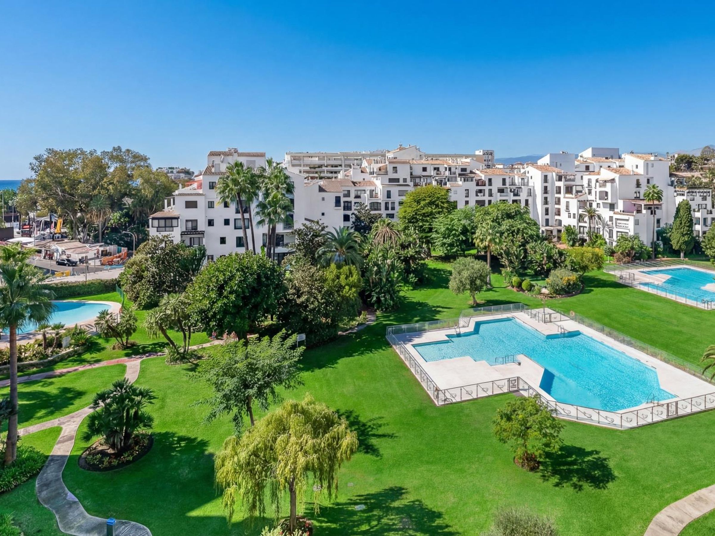 Un complexe hôtelier doté de plusieurs piscines, de vastes pelouses verdoyantes et de bâtiments blancs agrémentés de balcons.