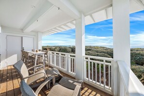 A covered outdoor area with a table and chairs, a white door, and a view of the landscape. - Gulf-Front WaterColor "Petite" Corner Condo for 2!  Couple's Beachfront Getaway! (Santa Rosa Beach)