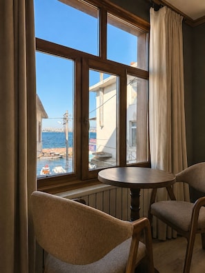 A room with a view of the sea, a table, and two chairs.