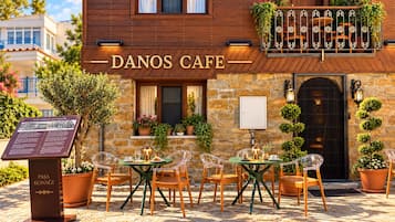A cafe with outdoor seating, a stone facade, and a signboard.