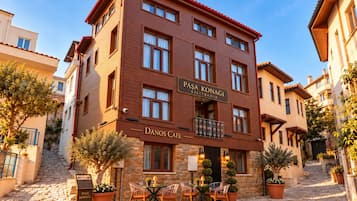 Ein Gebäude mit einem Schild für 'Pasa Konağı Kilitbahir' und 'Danos Cafe', inklusive Außenbereich mit Sitzgelegenheiten.