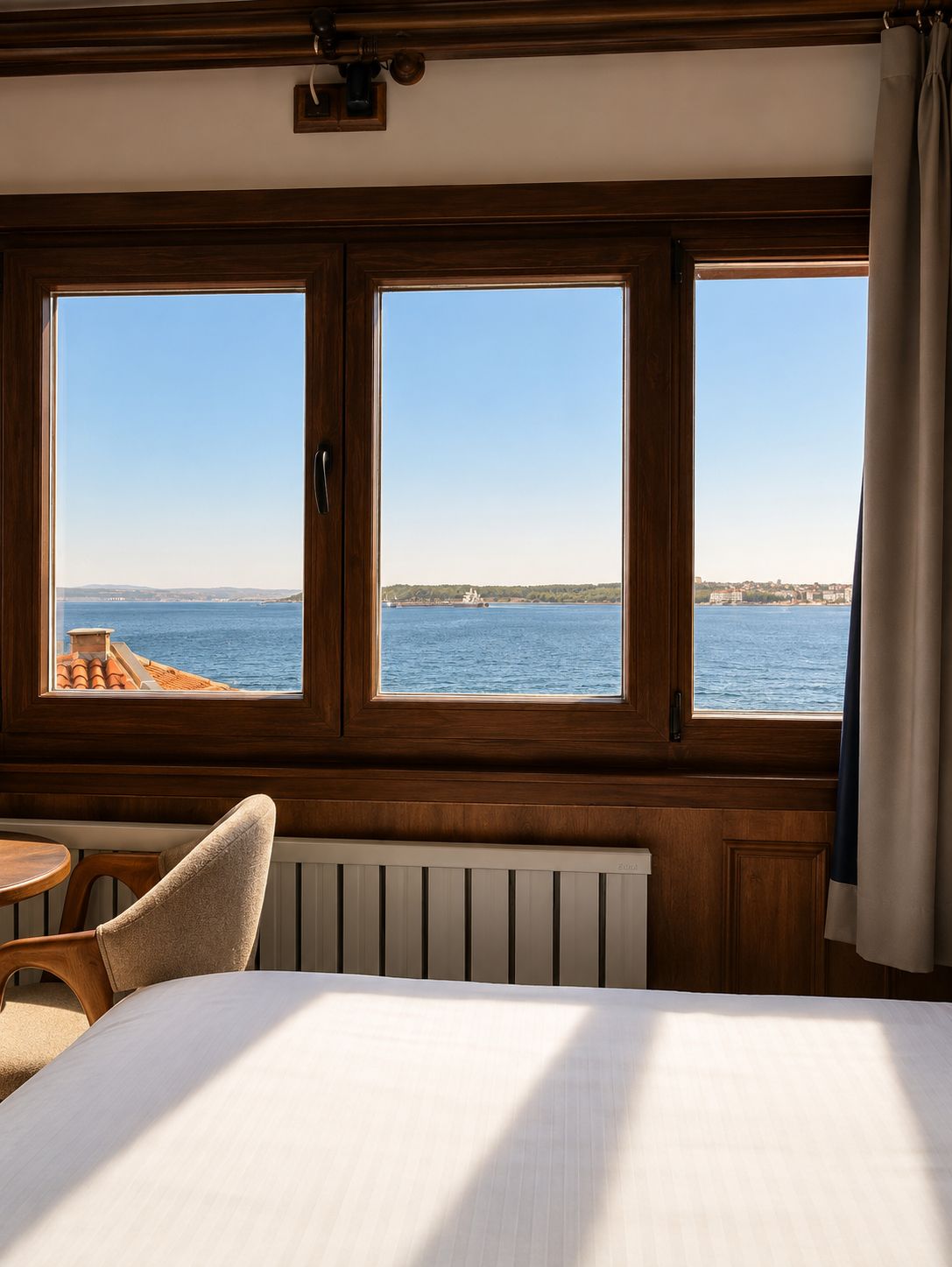 Une chambre avec un lit, une chaise et une vue sur la mer grâce à de grandes fenêtres.