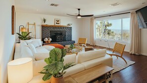 Ein modernes Wohnzimmer mit Kamin, Sitzecke und großen Fenstern.