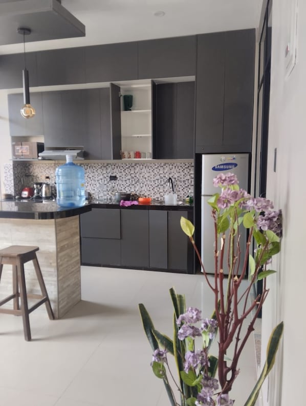 Una cocina moderna con armarios oscuros, un dispensador de agua y un refrigerador Samsung.