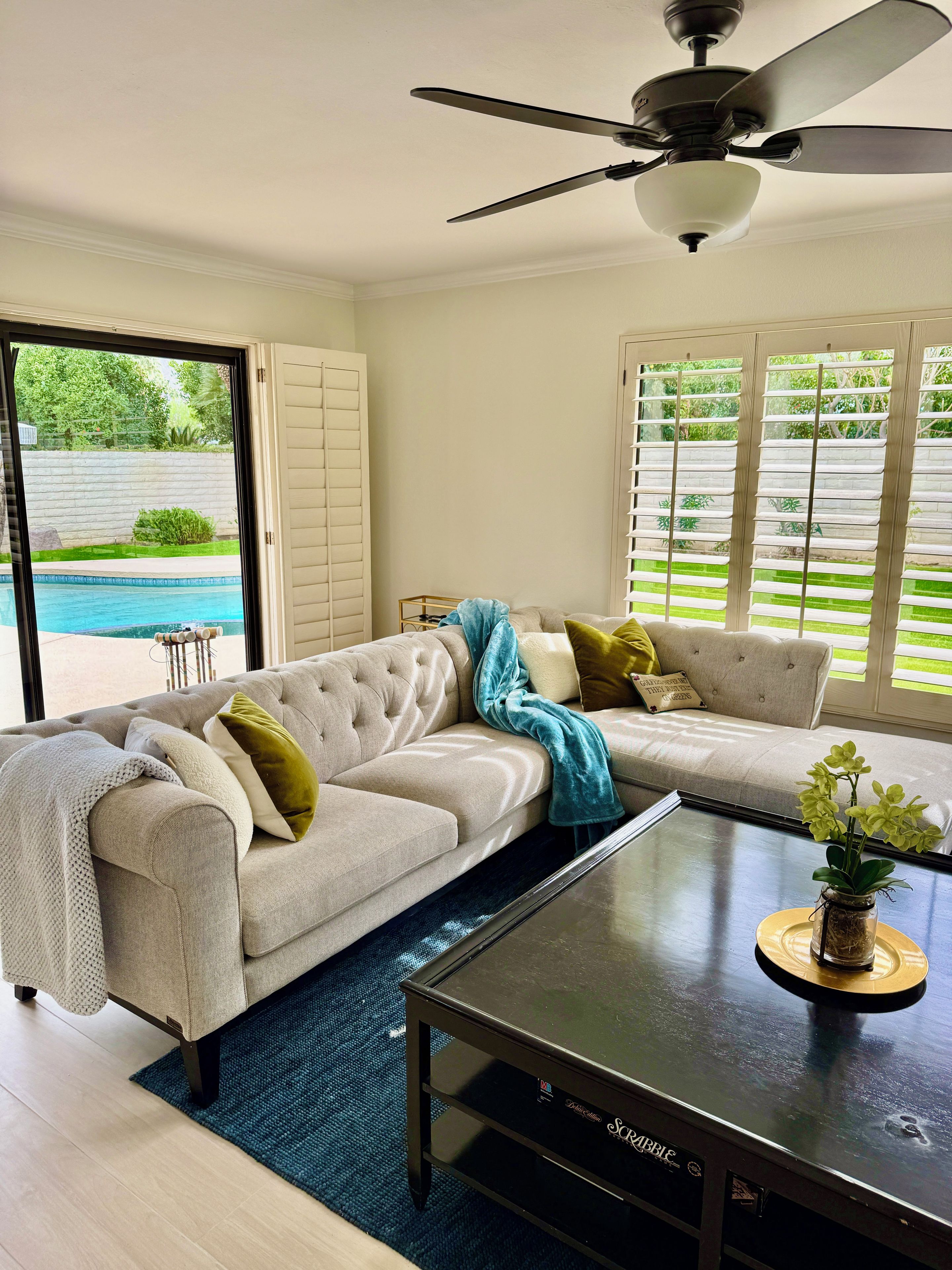 A living room with a sectional sofa, a coffee table, and a ceiling fan.