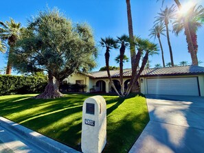 A residential property with a well-maintained lawn, a mailbox, and a garage. - Olive Tree Oasis ~ Charming 3B Indian Wells Home (Indian Wells)