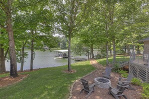 A lakeside deck with Adirondack chairs, a fire pit, and a dock extending into the water. - Just a short path to the lake! Private dock! 4 BR 4 BA (Estill Springs)