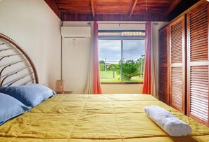 Una cama con una colcha amarilla, una toalla blanca y un cabecero de madera.