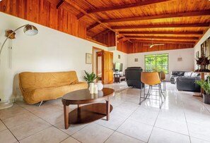 A spacious living area with a wooden ceiling, a sofa, a coffee table, and a TV. - Private Gated Pickleball & Pool Retreat Near beach (Parrita)