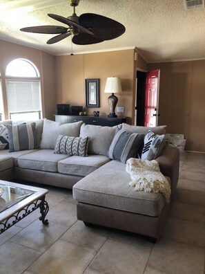 A living room with a sectional sofa, a coffee table, and a ceiling fan. - Newly renovated 2bedroom mobile home centrally located in Fort Myers@Jamaica Bay (Fort Myers)