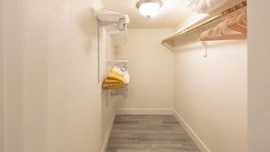 Un couloir étroit avec un plancher en bois, un mur blanc et un luminaire au plafond.