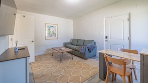 Un espace de vie compact comprenant un canapé, une table basse, une table à manger avec des chaises et un tapis à motifs.