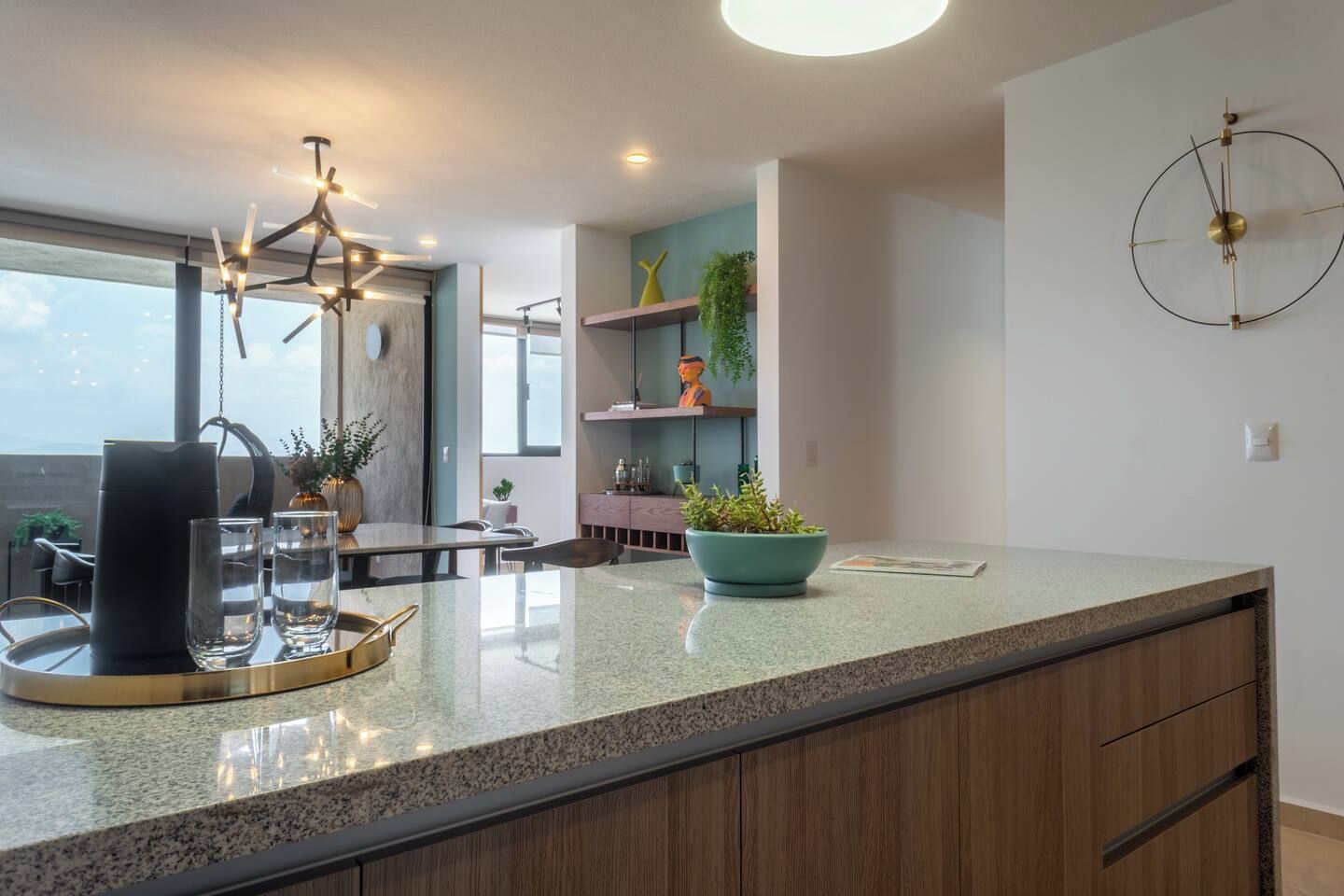Une cuisine moderne dotée d’un plan de travail en granit, d’un luminaire suspendu et d’une horloge murale.