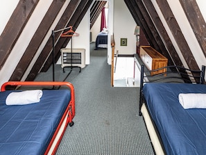 A small, compact room with two beds, a heater, a mirror, and a wooden cabinet. - The Mountain Nook -  Ohakune Holiday Home (Ohakune)