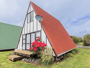 A triangular house with a satellite dish, a wooden deck, and red flowers. - The Mountain Nook -  Ohakune Holiday Home (Ohakune)