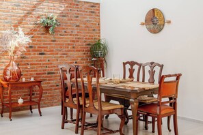 A dining area with a brick wall, wooden table, and chairs. - Charming house with garden and spaciousness in Juriquilla (Juriquilla)
