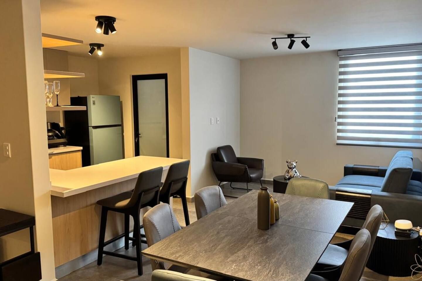 A compact living space with a kitchenette, a dining area, and a seating area with a sofa and chairs.