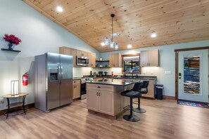 Una cocina moderna con armarios de madera, electrodomésticos de acero inoxidable y una isla central con taburetes de bar.