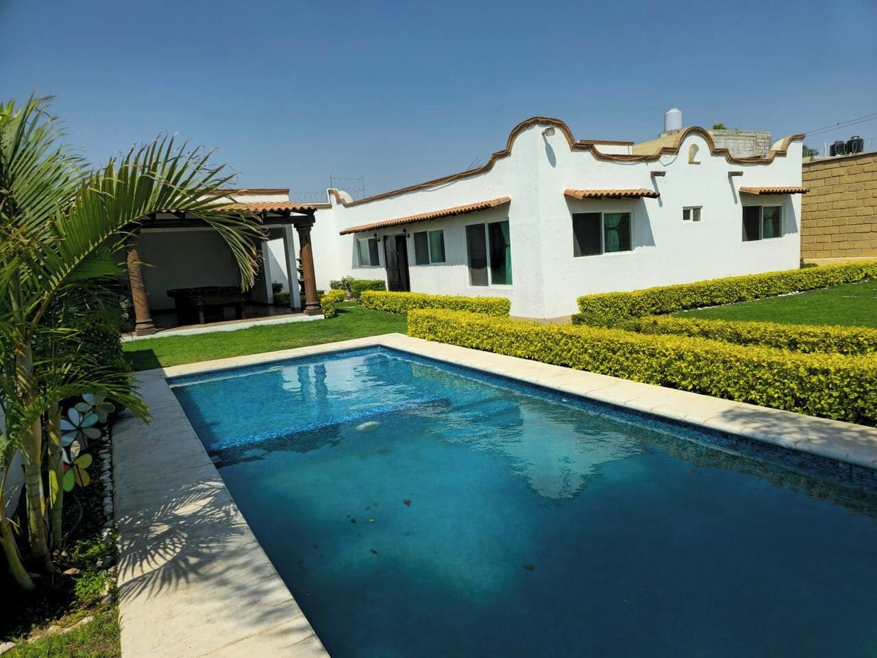 Una piscina con un edificio blanco al fondo.