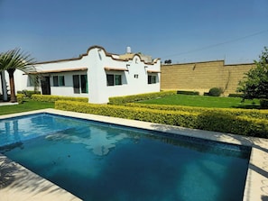 Una piscina con un edificio blanco al fondo.