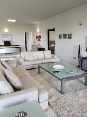 Ein modernes Wohnzimmer mit einer Couch, einem Glastisch und einem Fernseher.