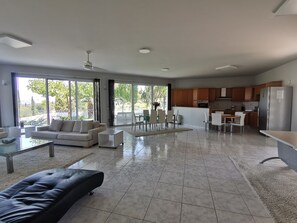 A modern living space with a sofa, dining table, and kitchen area. - Mythos luxury ground-floor apartment 3 (Kerkyra)