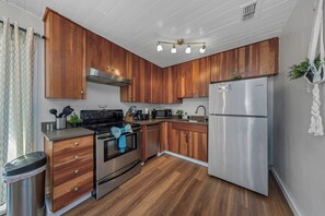 Una cocina moderna con armarios de madera, electrodomésticos de acero inoxidable y piso de madera.