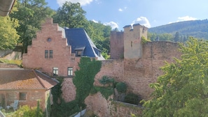 En historisk bygning i sten med et stejlt tag, et lille tårn og en omgivende mur.