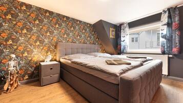 A bedroom with a bed, nightstand, and a decorative skeleton.