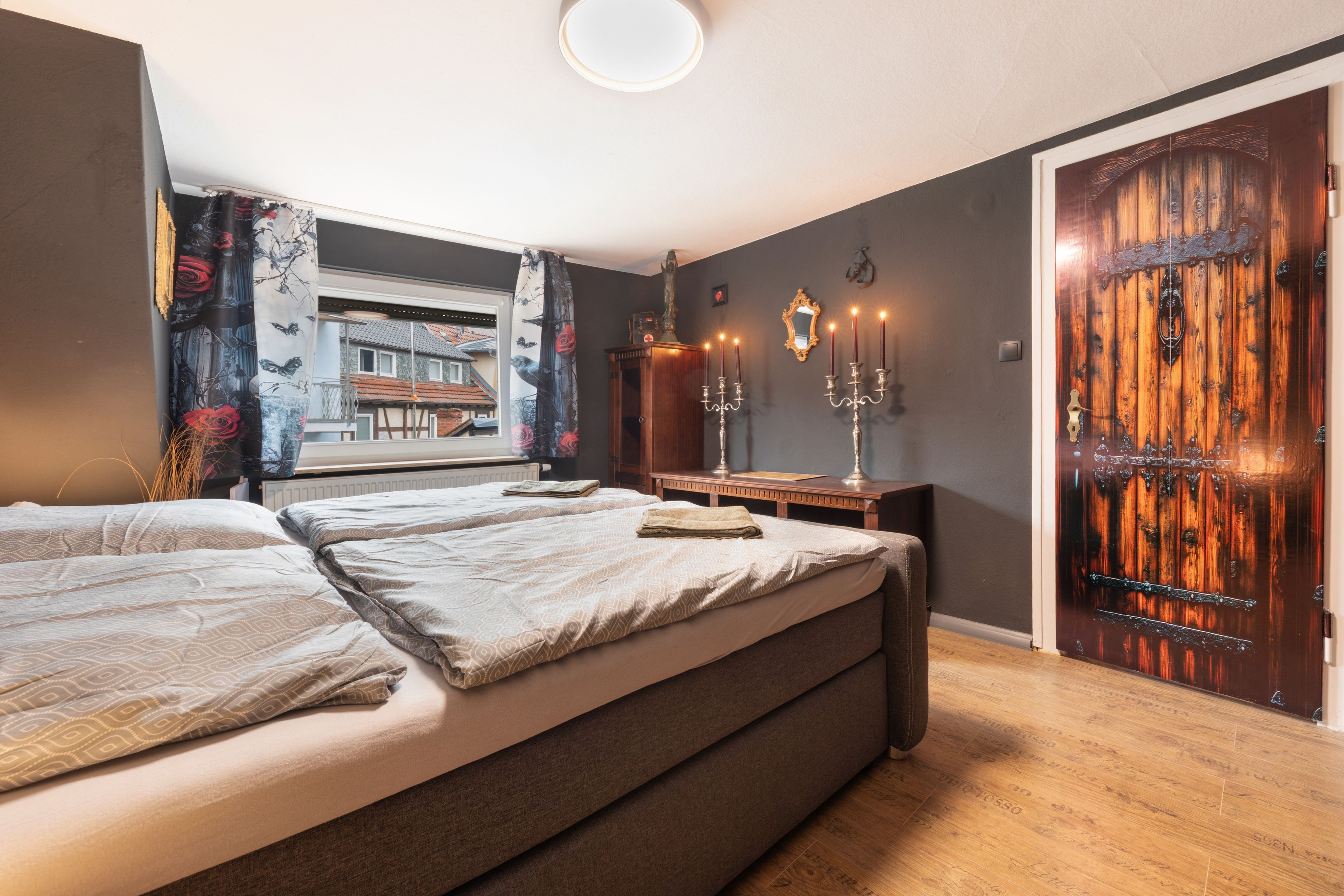 A bedroom with a large bed, a wooden door, and a window with curtains.