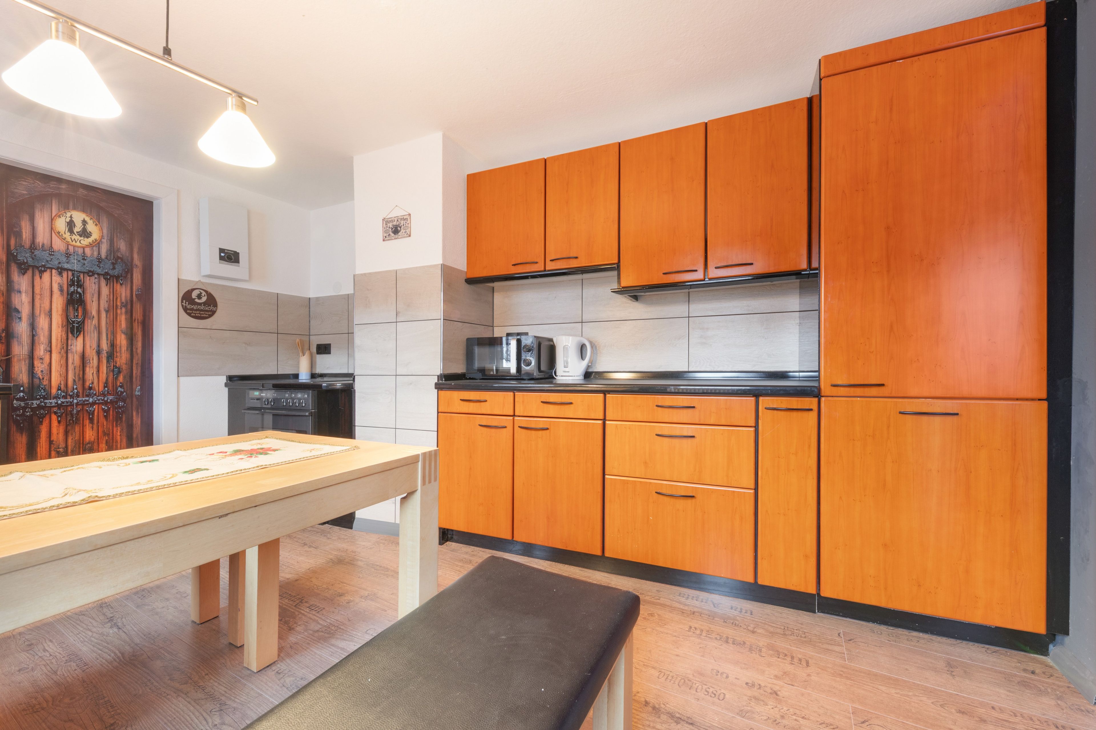 A kitchen with wooden cabinets, a stove, and a table with a bench.